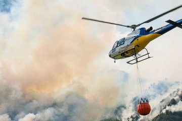 helicopter flying over wildfire smoke
