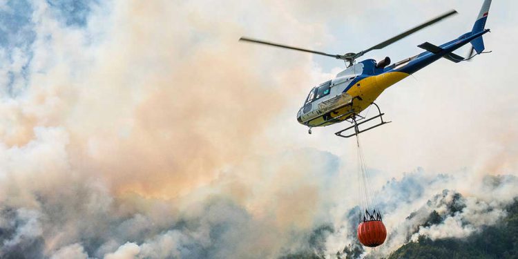 helicopter flying over wildfire smoke